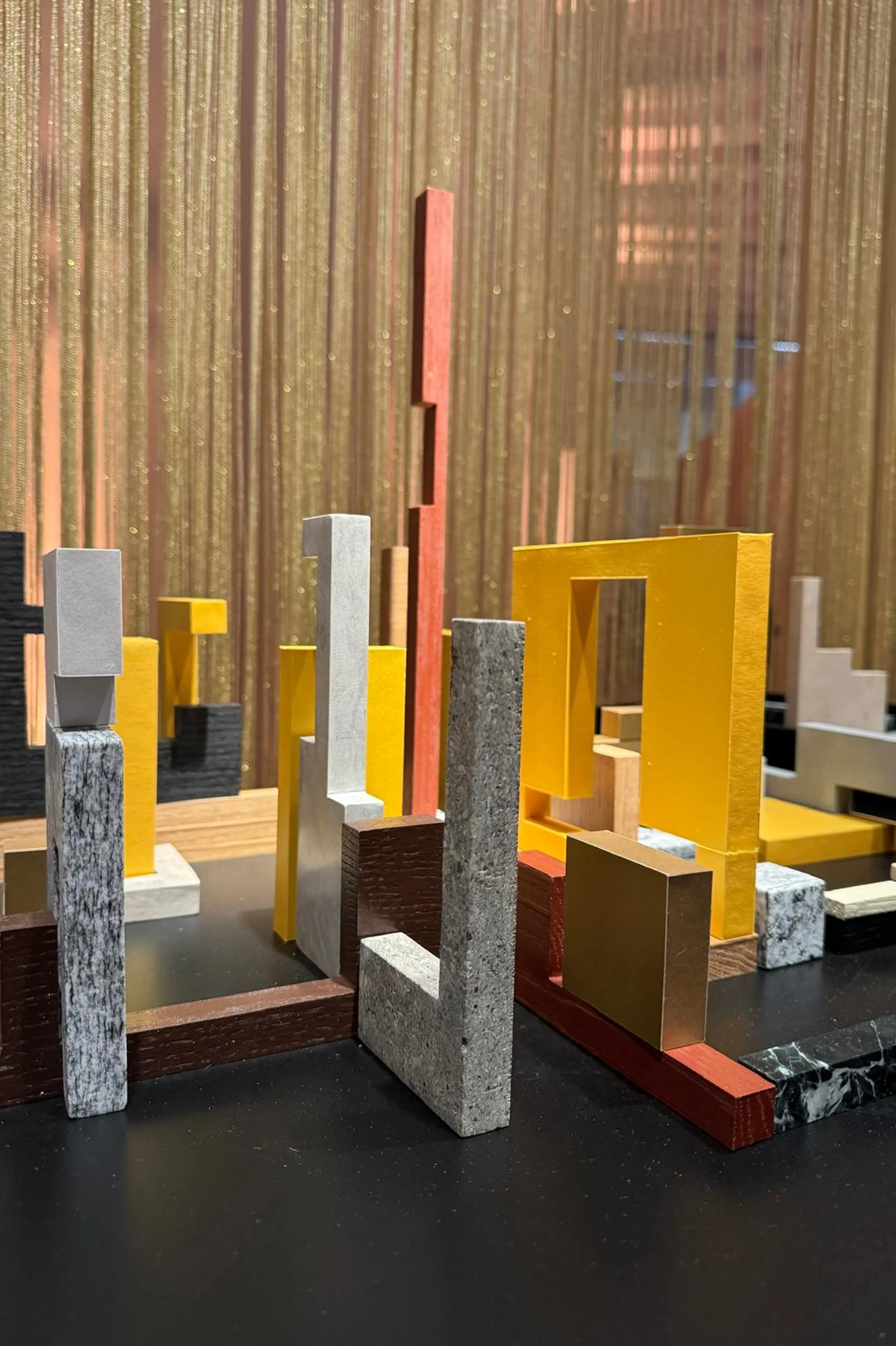 Dettaglio frontale di Forme di Dialogo - moduli in Grigio Alpi e Quarzite Grigia a contrasto con elementi dorati e in legno rosso, installazione artistica in marmo e pietre naturali Trapattoni Marmi, Triennale di Milano 2025