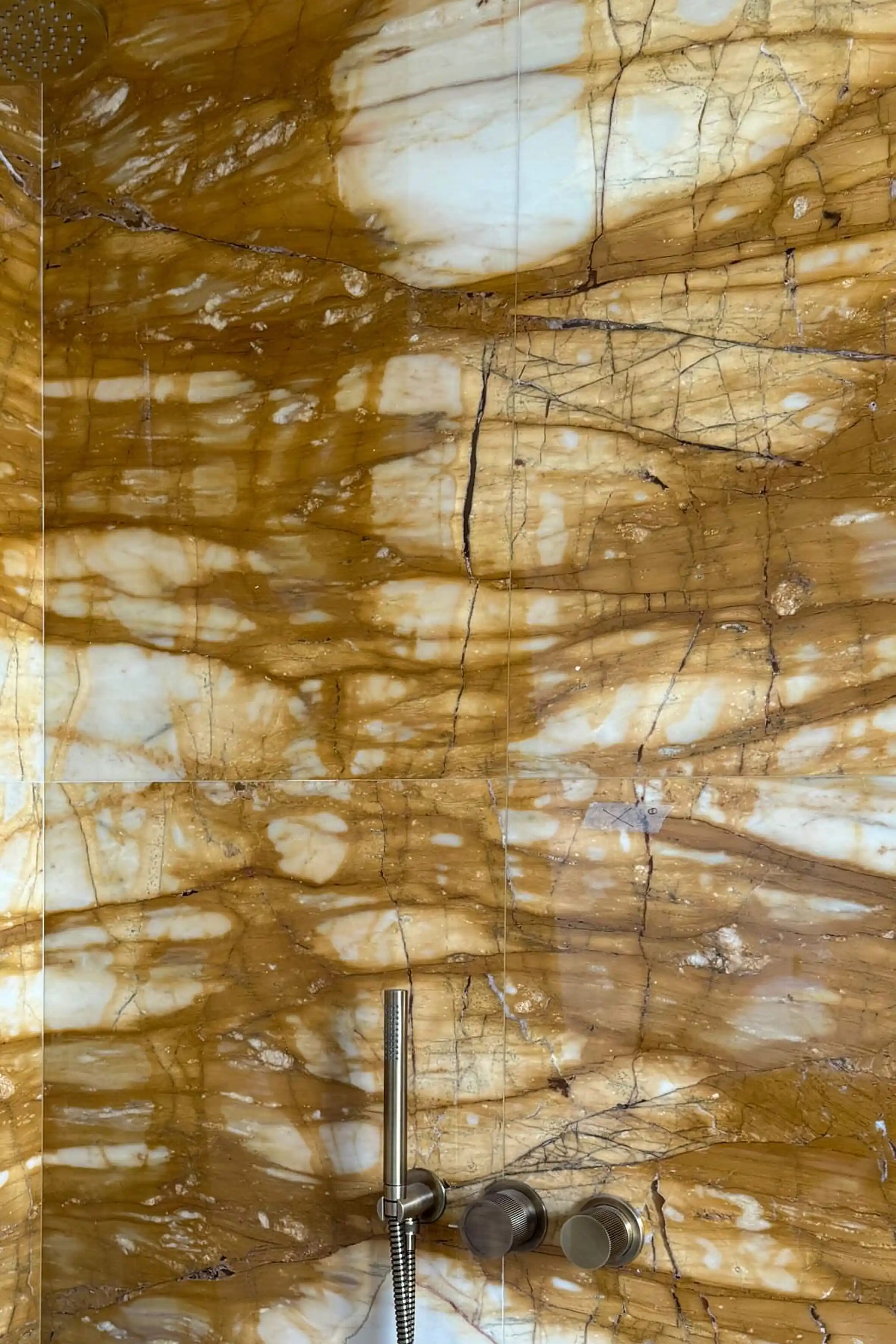 Rivestimento a parete della doccia in Giallo Siena lucido con venature ambrate e macchie bianche, miscelatore e doccetta a vista - bagno master LC Castello in fase di realizzazione, posa in opera Trapattoni Marmi Bergamo