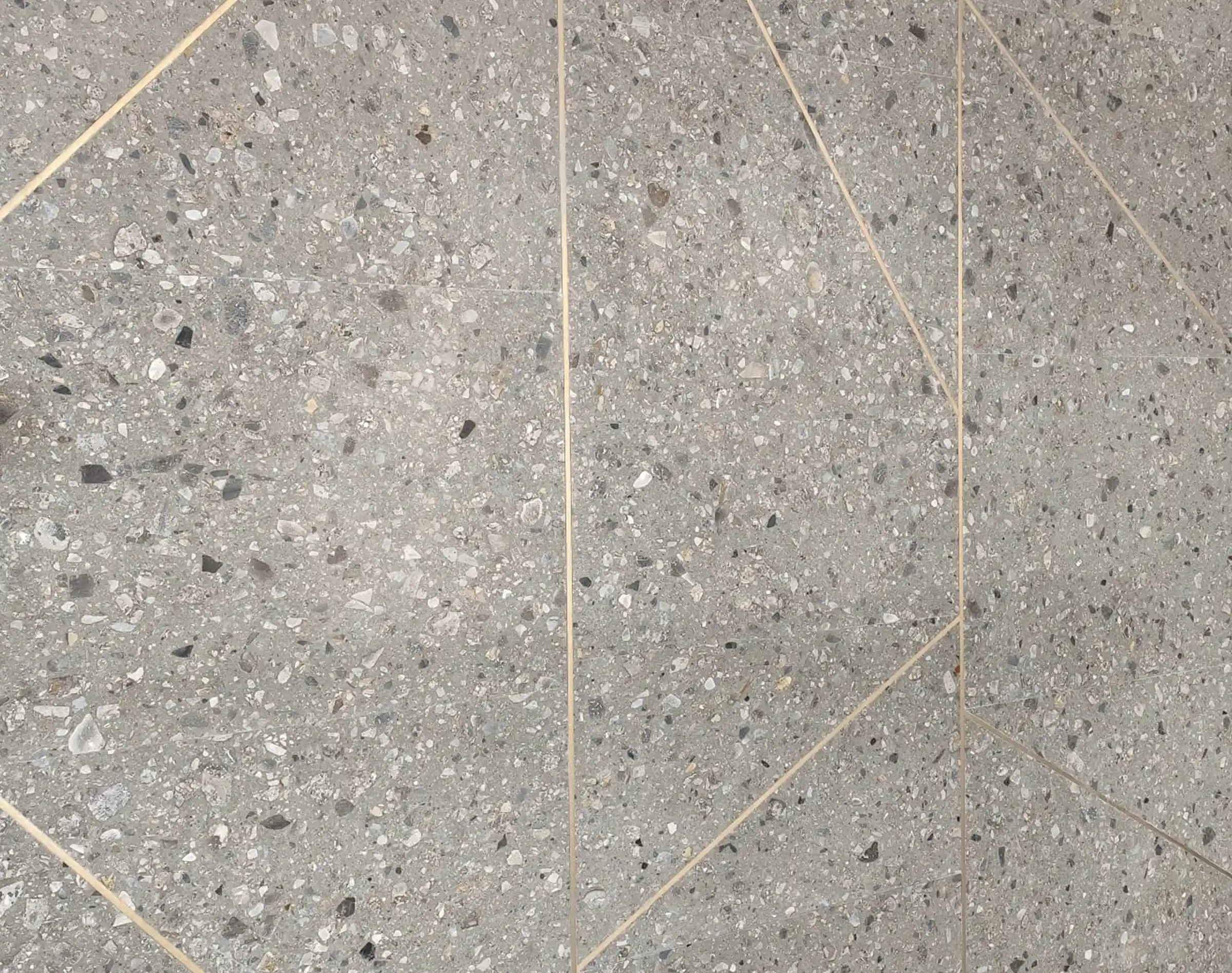 Dettaglio della pavimentazione della hall d'ingresso in Agglotech SB130 Aggloceppo levigato con fasce decorative diagonali in ottone - lavorazione artigianale su misura Trapattoni Marmi per il complesso residenziale Adamello, Milano