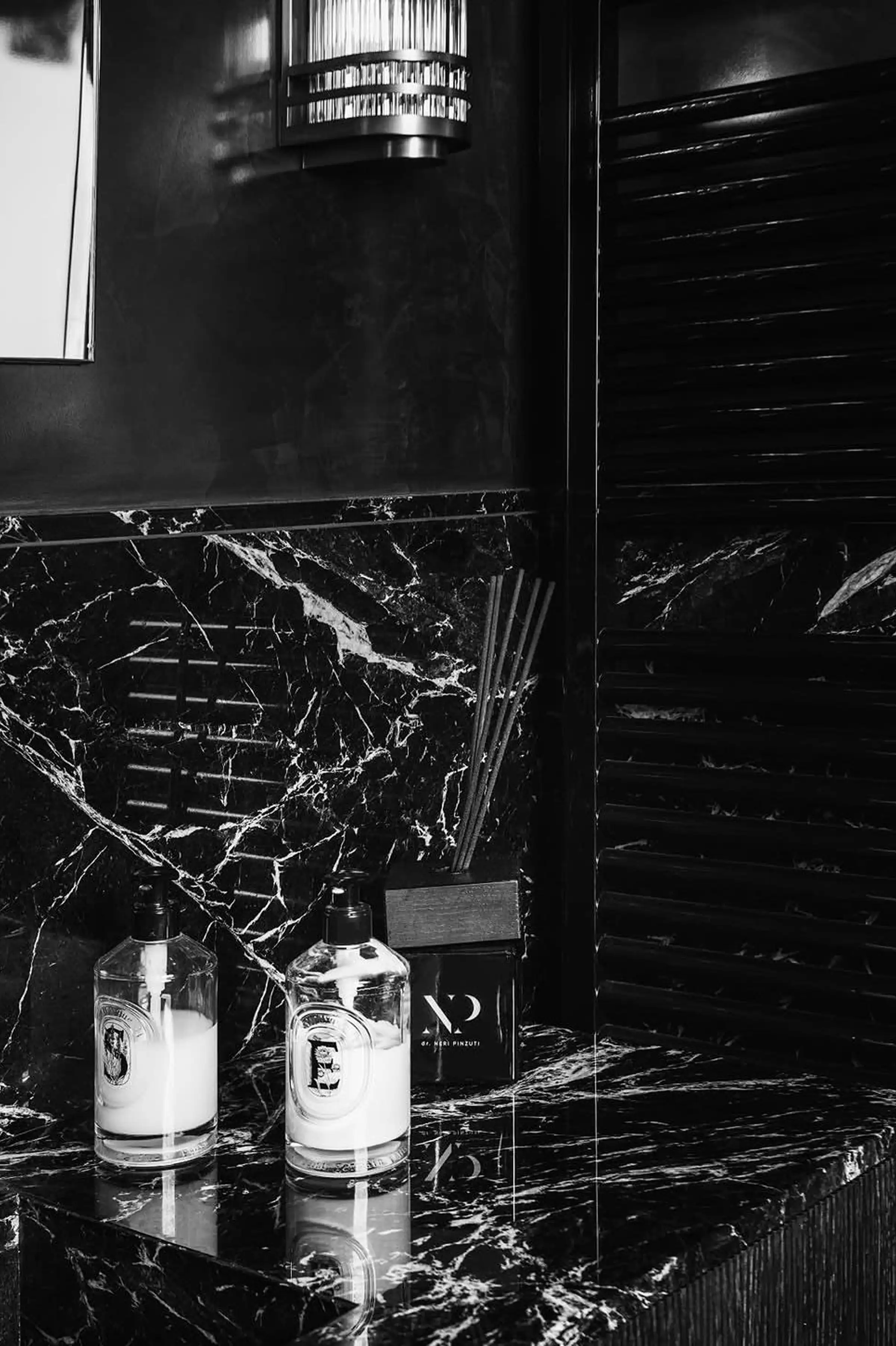 Dettaglio bagno in Portoro lucido con diffusori e prodotti su piano in marmo nero e oro - studio dentistico Pinzuti a Milano, lavorazione artigianale Trapattoni Marmi Bergamo