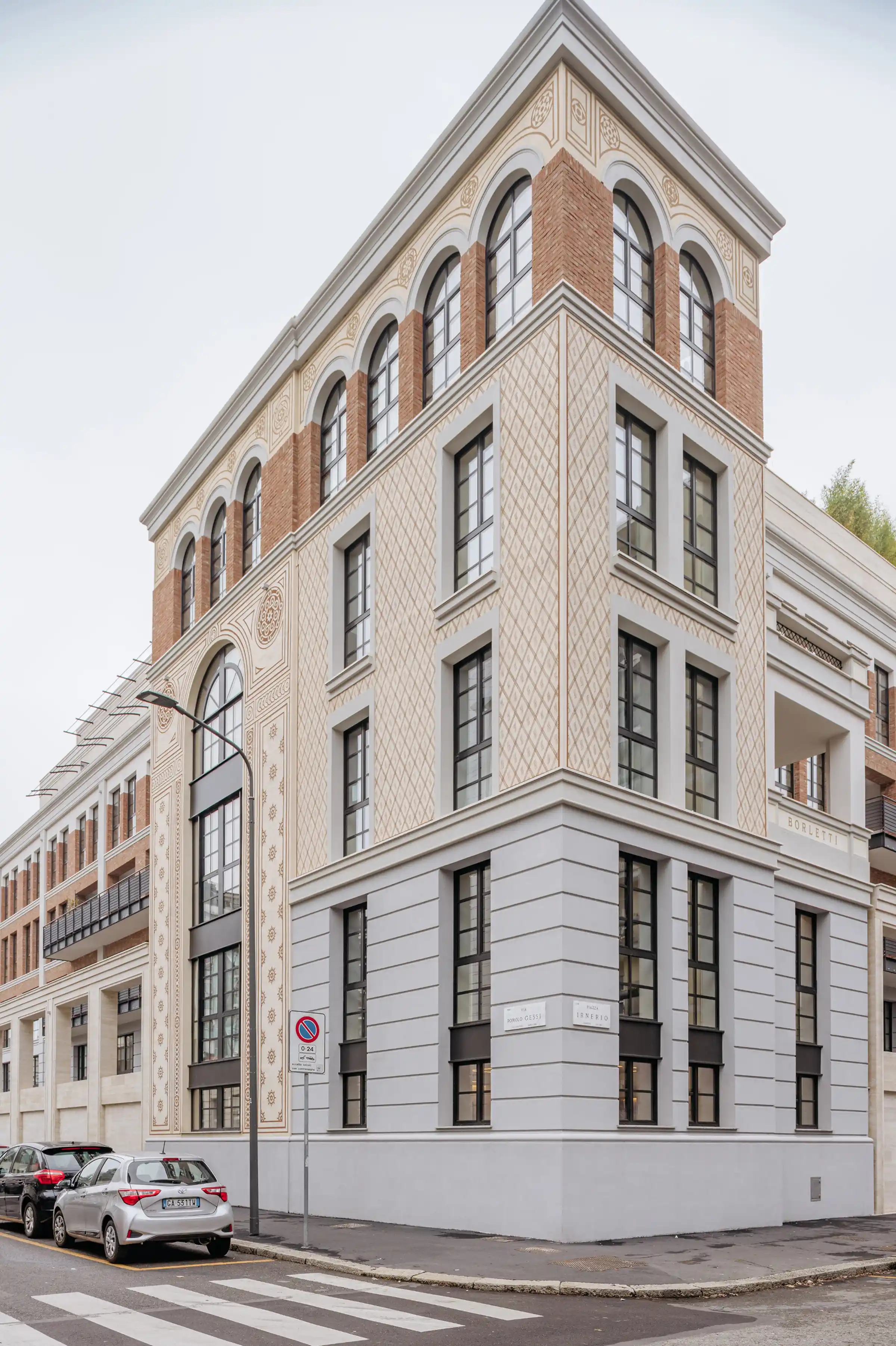 Facciata del Washington Building a Milano con torre d'angolo decorata in Travertino Romano: modanature a motivi geometrici, archi a tutto sesto con ghiere in pietra, mattone a vista e cornicioni - Trapattoni Marmi, quartiere Washington