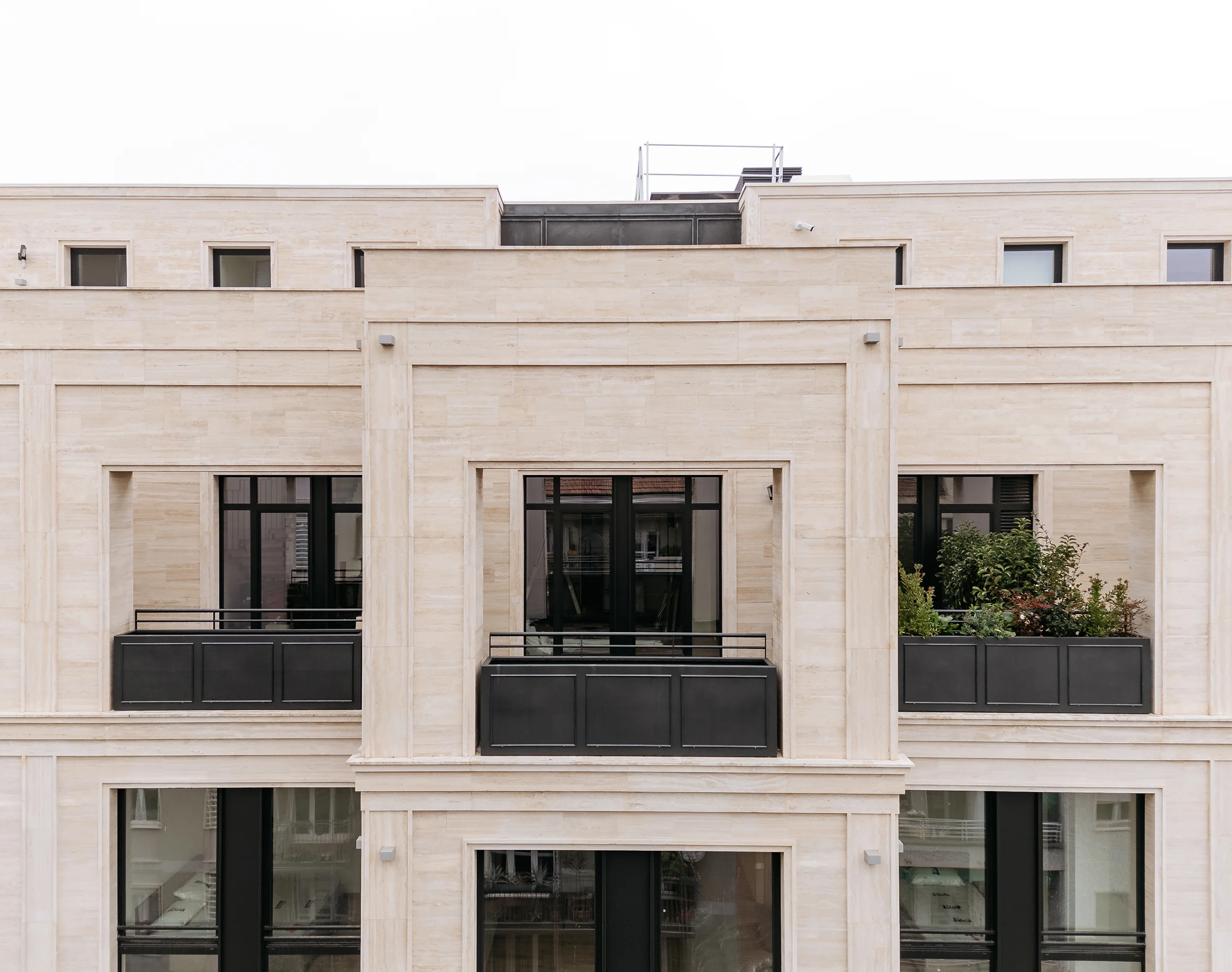 Lungo prospetto del Washington Building a Milano con loggiato ad archi, cornicioni e fasce in Travertino Romano, paramento in mattone a vista rosso e corpi scala aggettanti - riqualificazione storica fabbrica, Trapattoni Marmi