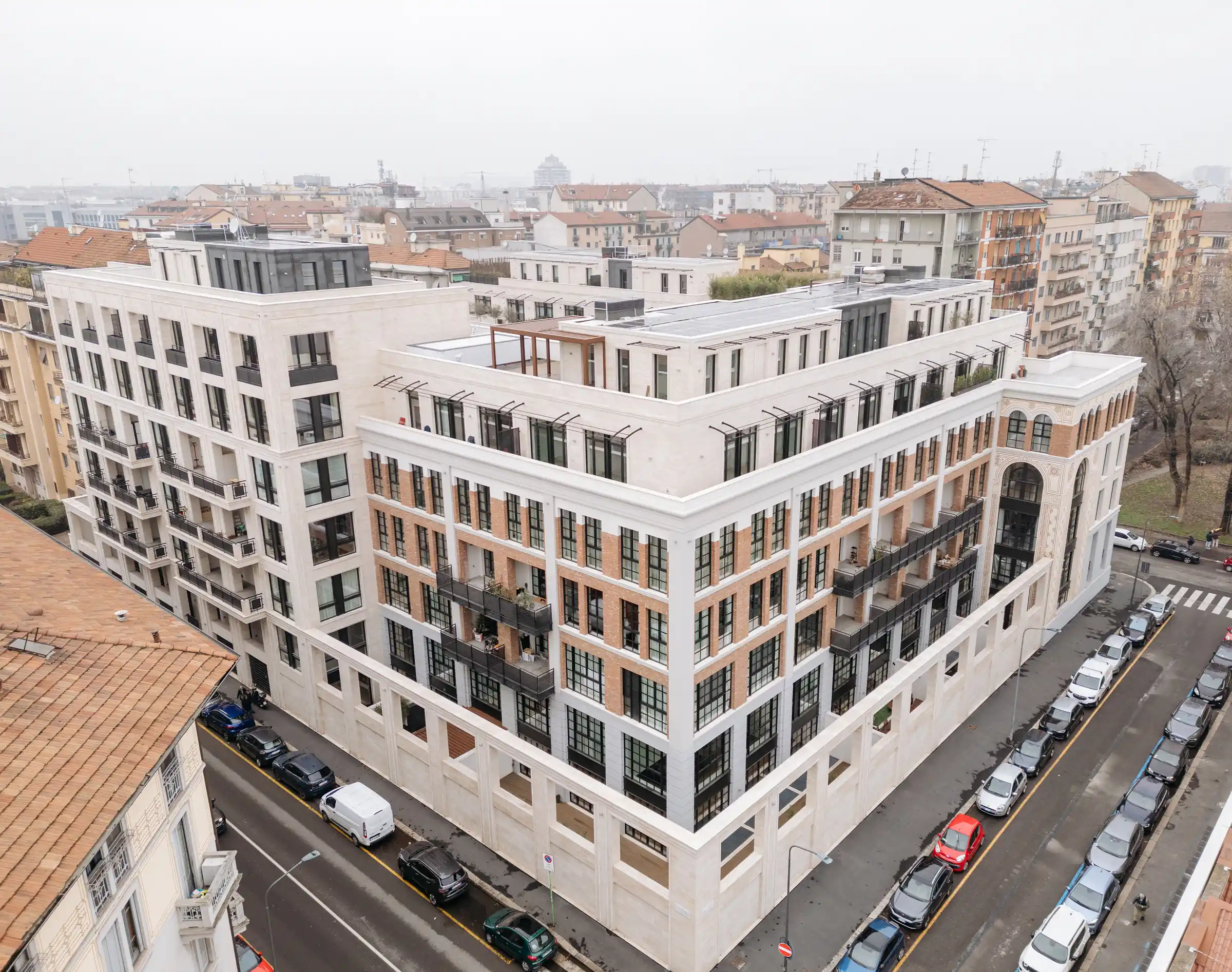 Dettaglio dell'angolo del Washington Building a Milano: cornicioni, lesene e fasce marcapiano in Travertino Romano con paramento in mattone rosso, balconi con parapetti in acciaio e piano attico in pietra - Trapattoni Marmi