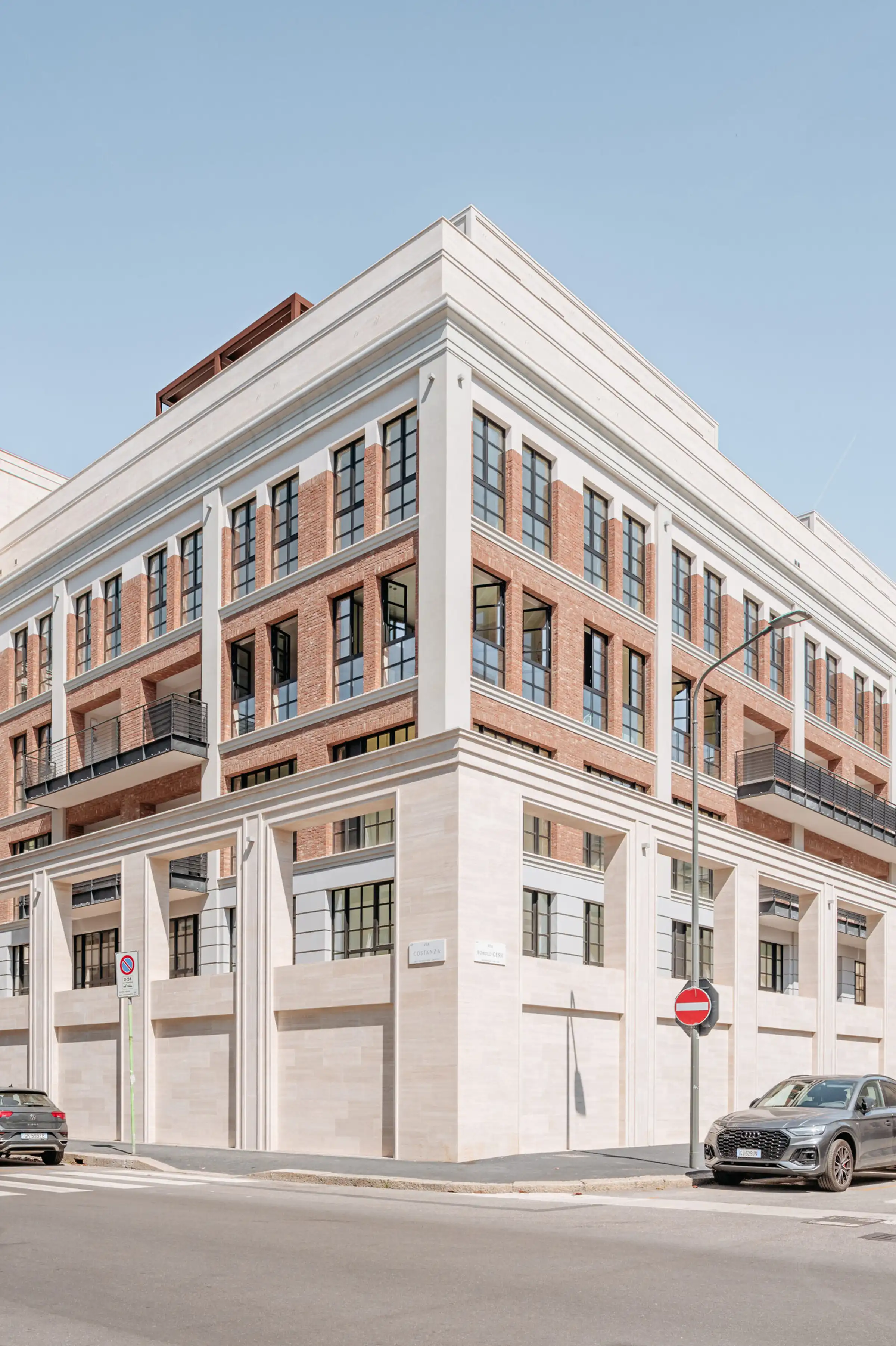 Angolo del Washington Building a Milano: basamento, cornicioni e lesene in Travertino Romano a contrasto con il paramento in mattone a vista rosso - intervento di riqualificazione di storica fabbrica nel quartiere Washington, Trapattoni Marmi