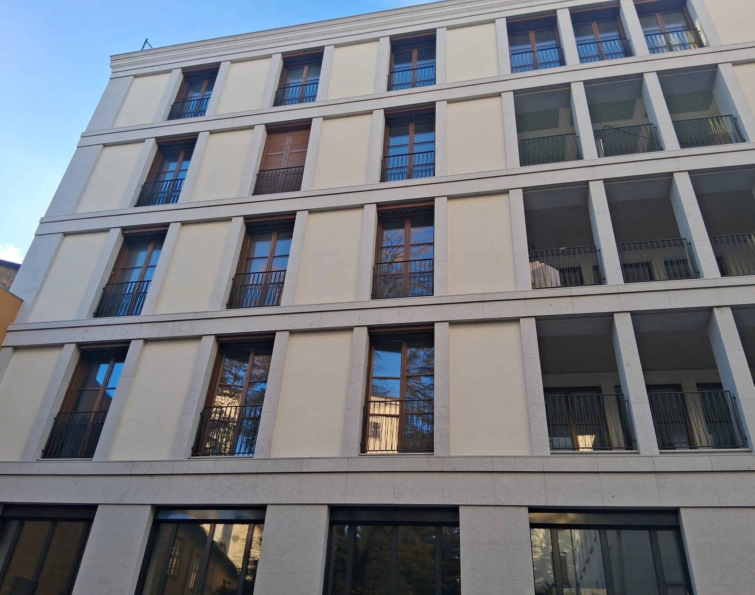Facciata completata del palazzo di Via Sassi a Milano in Granito Bianco di Montorfano levigato e granigliato: lesene verticali, fasce marcapiano, balconi in ferro e infissi in legno - fornitura e posa in opera Trapattoni Marmi, centro storico di Milano