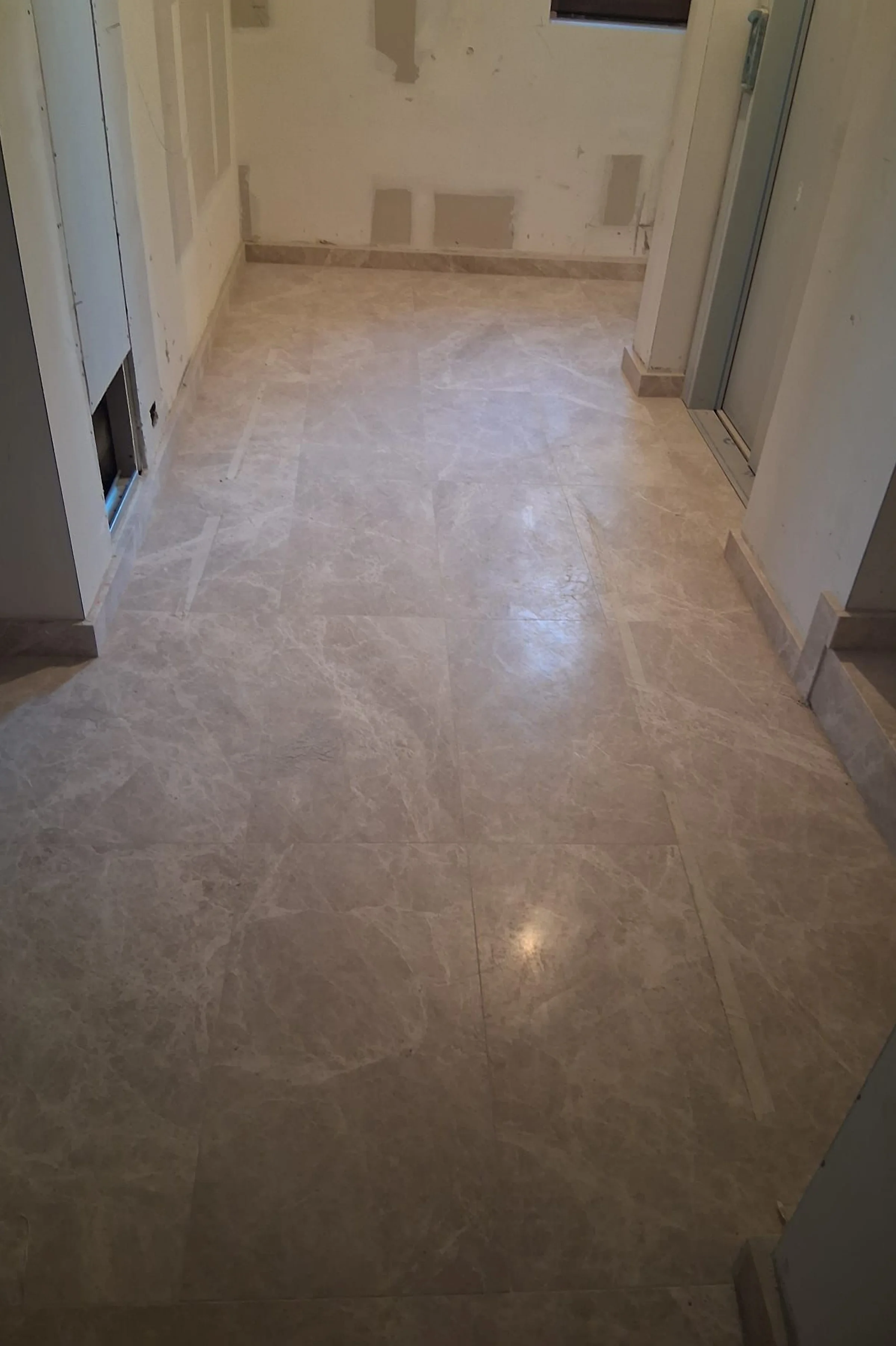 Pavimentazione degli spazi comuni in Emperador White levigato in fase di posa in opera nel palazzo di Via Sassi a Milano - lastre in marmo grigio chiaro con finitura lucida, lavorazione artigianale Trapattoni Marmi Bergamo
