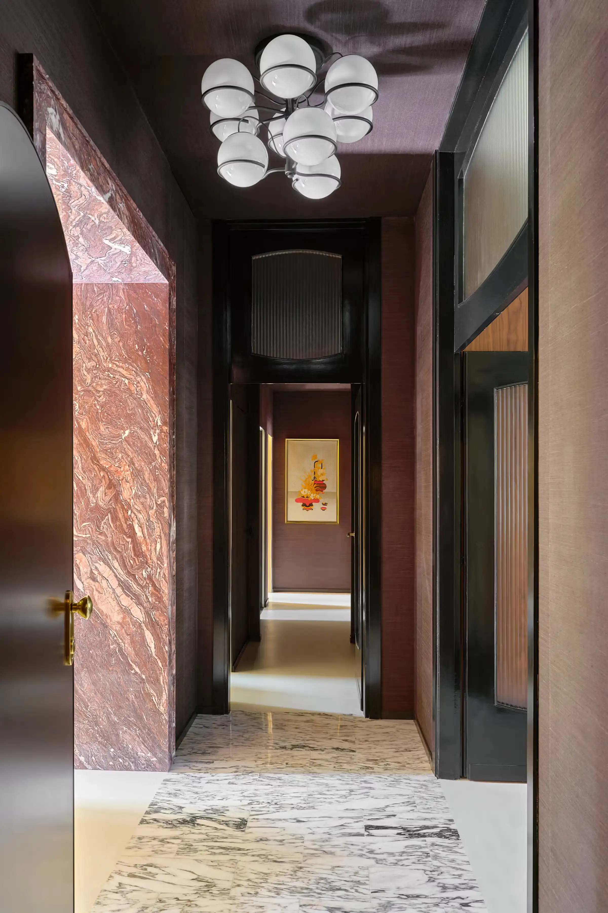 Portale d'ingresso rivestito in Cipollino rosso-viola con venature dinamiche rosse e arancio, corridoio con pavimento in marmo bianco venato, lampadario a sfere di vetro bianco e porte originali riverniciate - dimora ai Navigli, LC Atelier x Trapattoni Marmi