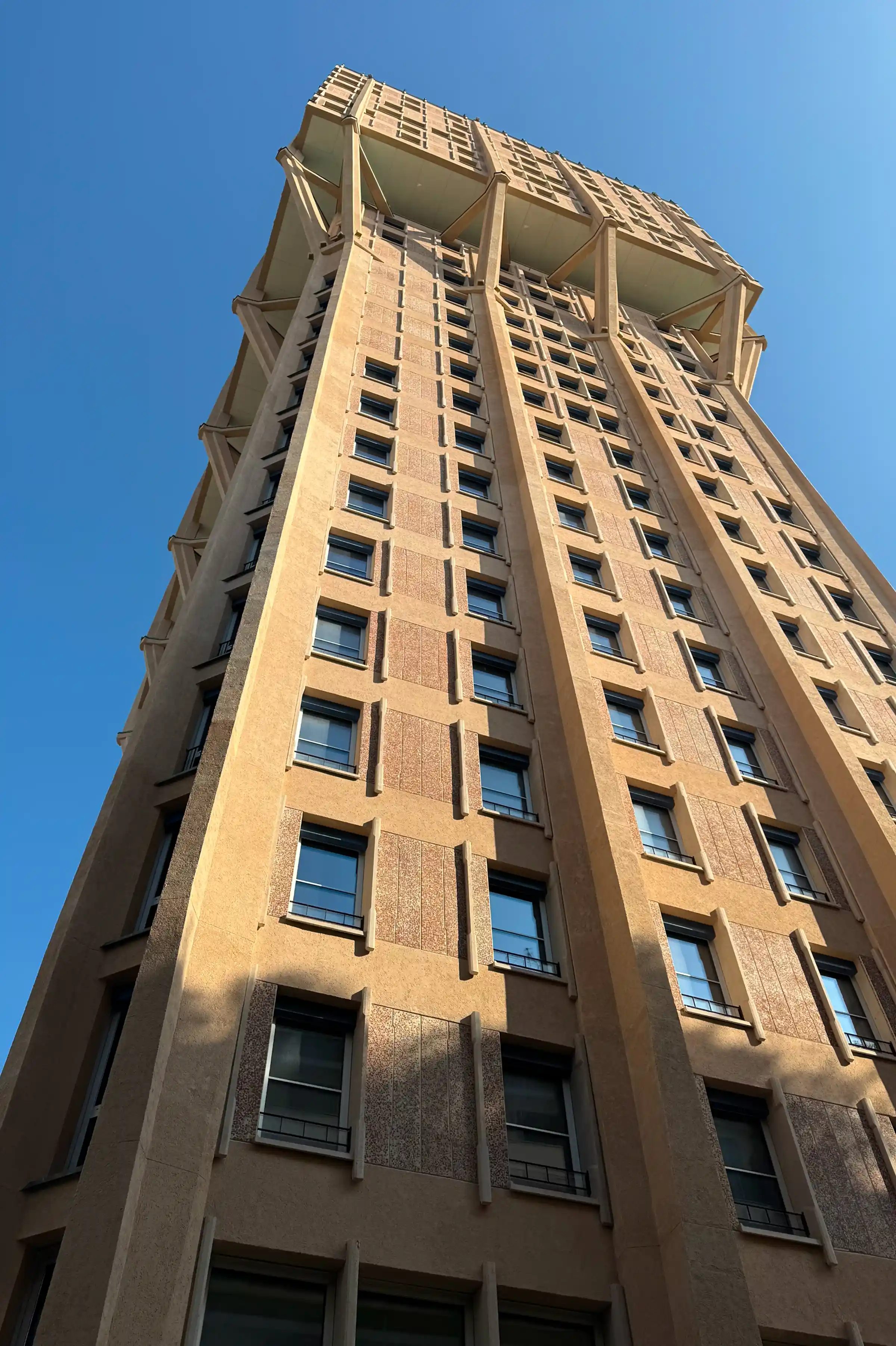 Prospetto laterale della Torre Velasca a Milano con facciata rinnovata in Trachite Euganea su cielo blu - restauro storico Piazza Velasca Trapattoni Marmi