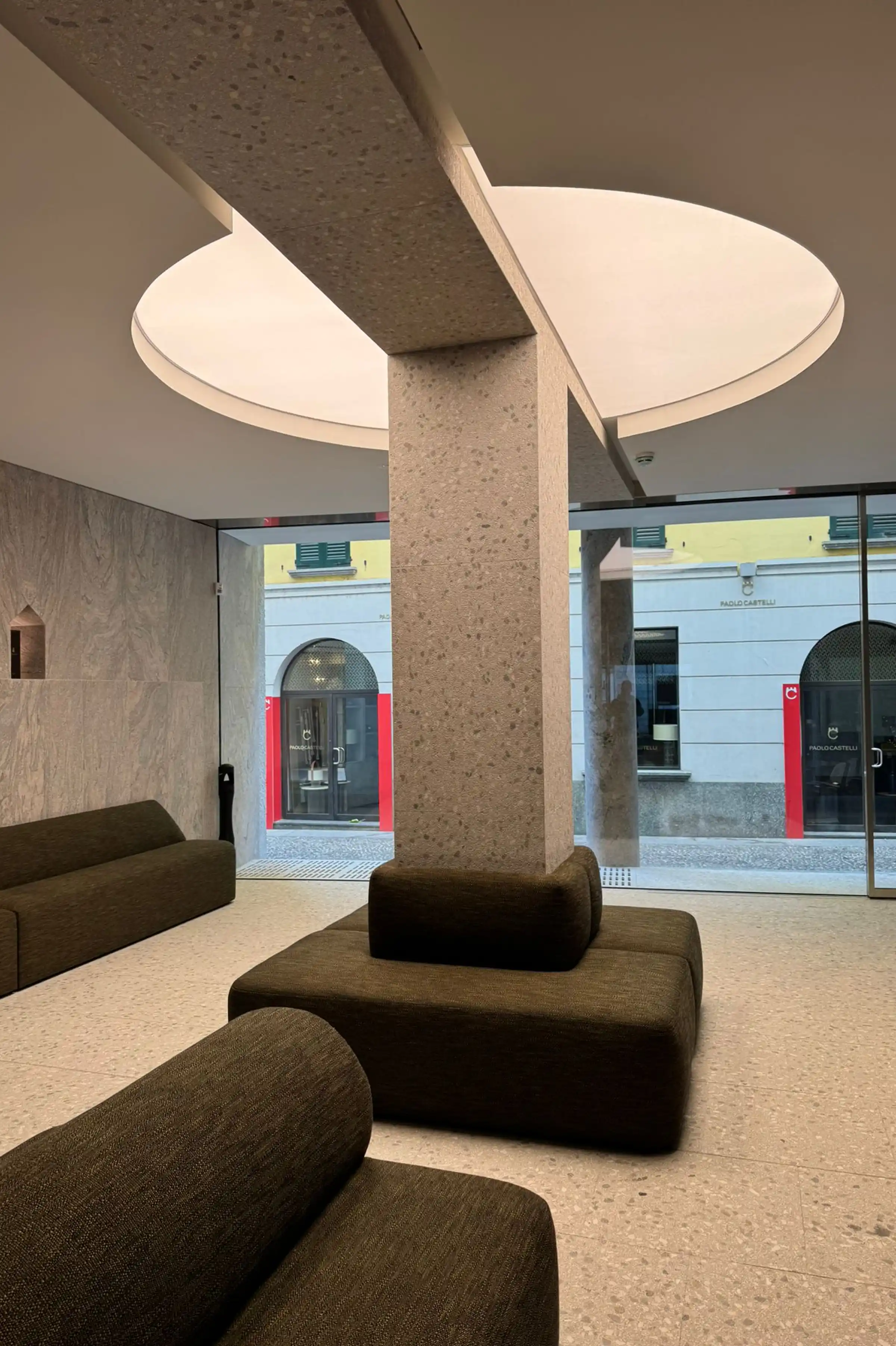 Colonna monolitica in Granito Juparanà Rosa e pavimento in Agglotech SB220 Giudecca sabbiato e spazzolato con lucernario circolare nello showroom di Via Fiori Chiari a Milano - Trapattoni Marmi