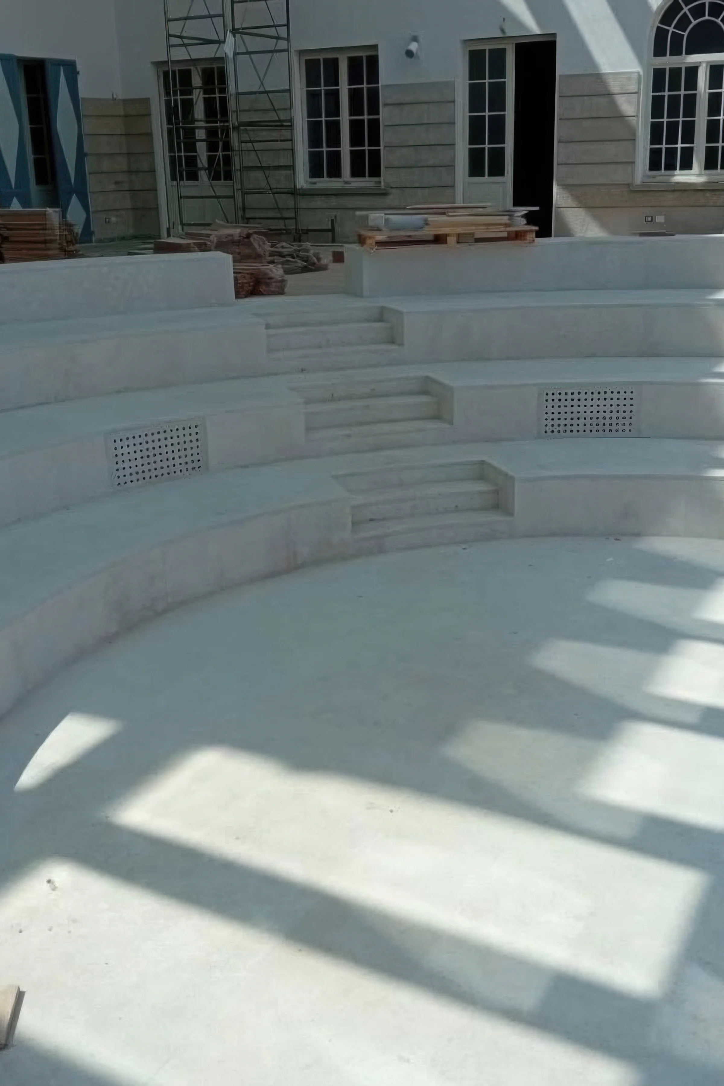 Anfiteatro a gradoni in Pietra d'Istria con sedute curve e scalinate centrali durante la fase di realizzazione presso la Fondazione Dalmine di Tenaris a Dalmine (BG) - Trapattoni Marmi