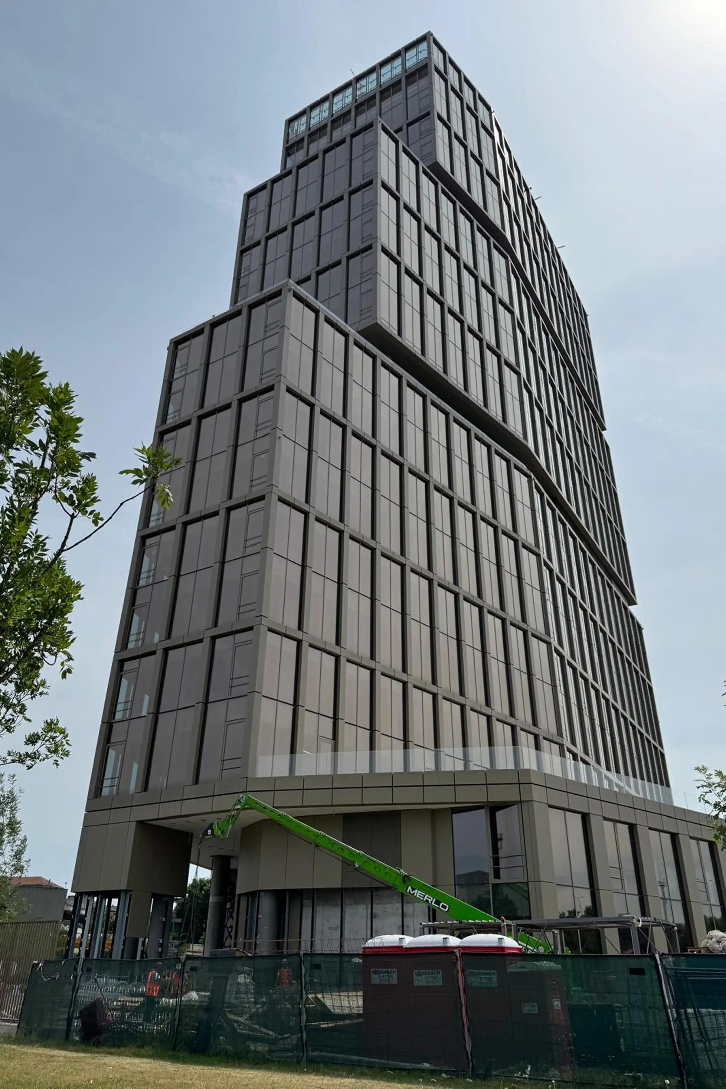 Vista esterna della TheTris Tower nel quartiere Famagosta di Milano progettata da Stefano Belingardi Architects con pavimentazione esterna in cubetti di Granito Giallo ad archi contrastanti - Trapattoni Marmi